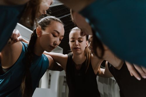 Free A dedicated group of female athletes huddling together in teamwork inside a gym. Stock Photo