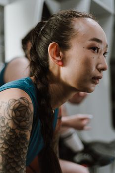 Side profile of a tattooed woman in sportswear sitting in a changing room.