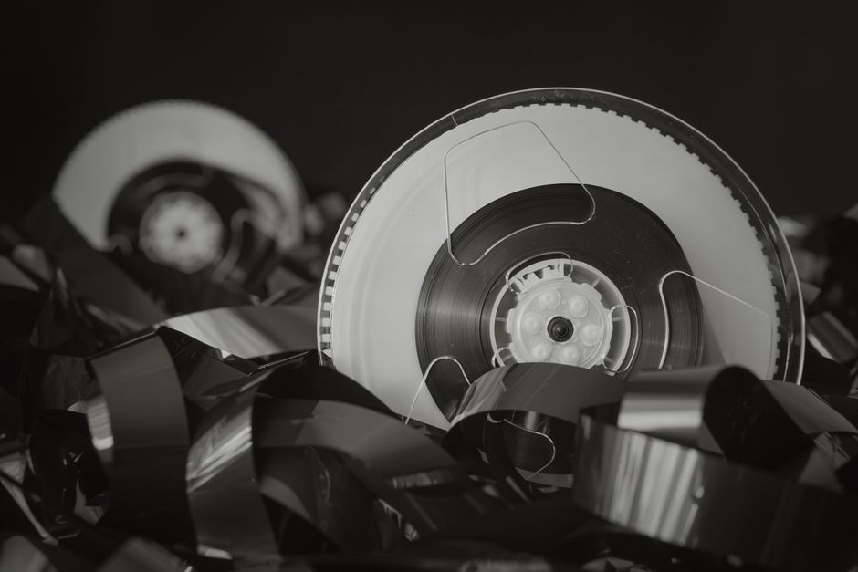 Close-up of vintage reel tape with tangled film, exuding a retro feel. Close-up of vintage reel tape with tangled film, exuding a retro feel.