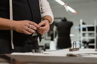 Close-up of a tailor using chalk and tape measure in a clothing atelier.