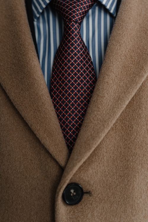 Free Close-up of a brown coat, striped shirt, and patterned necktie in formal attire. Stock Photo
