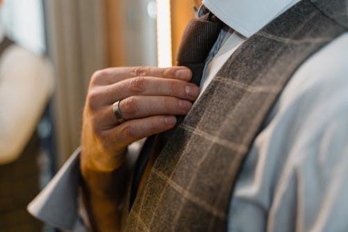 Person in Gray Suit Vest Holding His Necktie