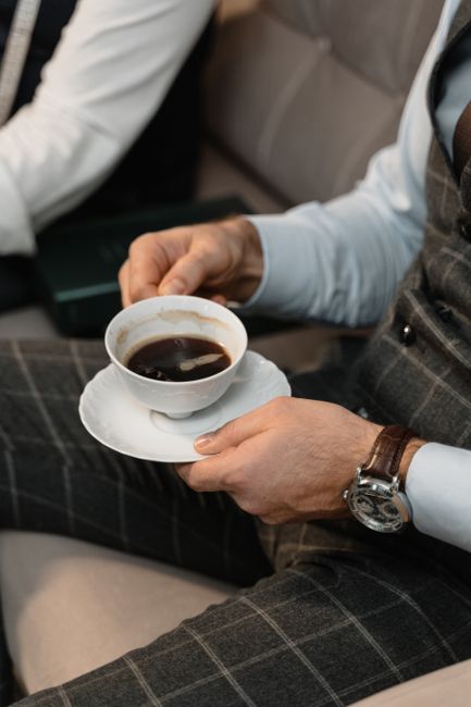 Businessman in a suit holding a cup of coffee, showcasing a relaxed and sophisticated setting. Businessman in a suit holding a cup of coffee, showcasing a relaxed and sophisticated setting.