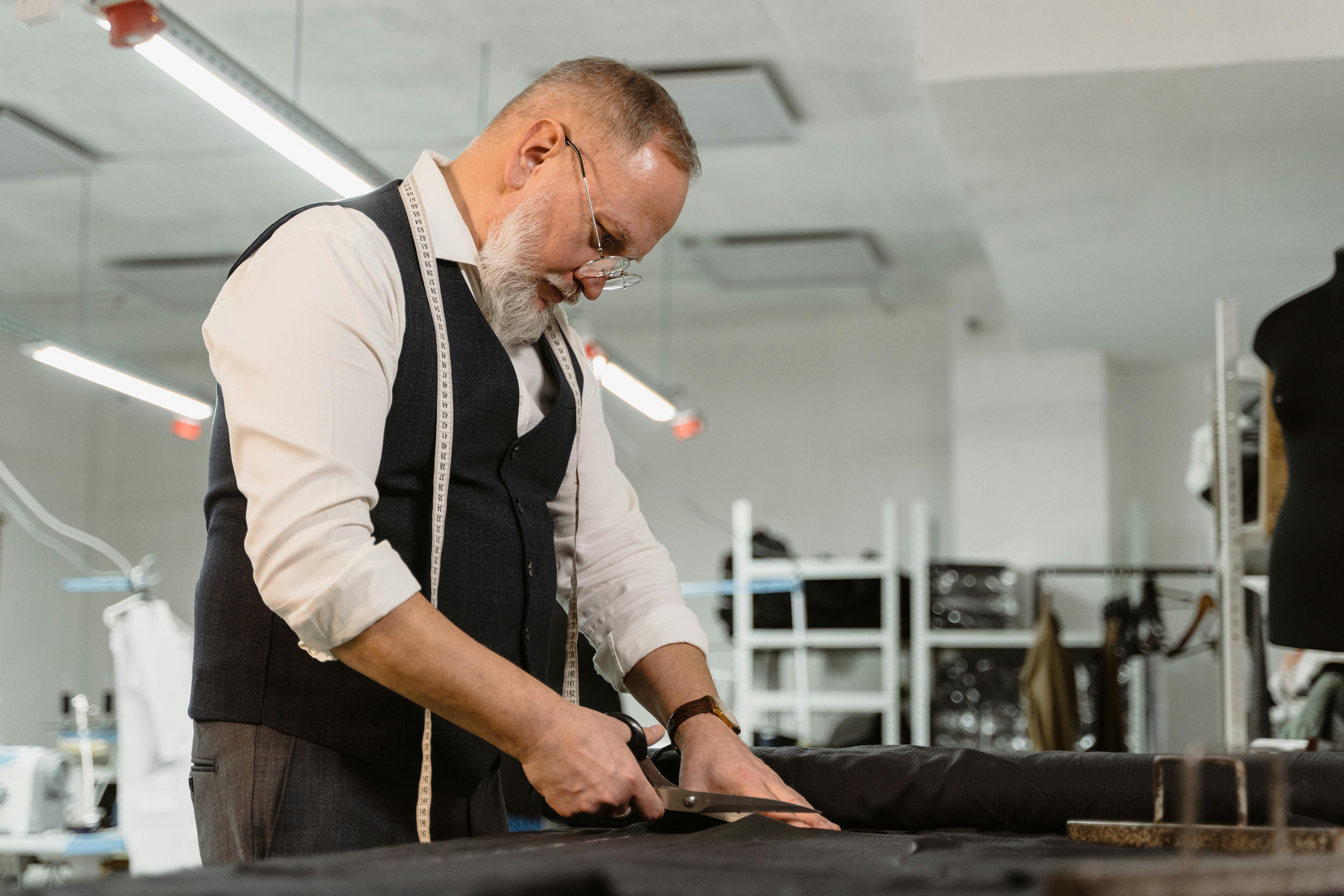 man in white dress shirt and black vest holding smartphone