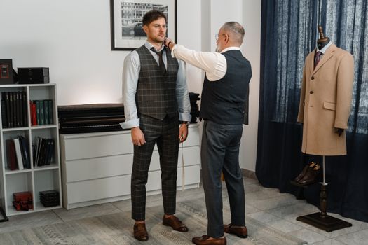 Tailor measuring a client's suit for a perfect fit in a stylish fashion studio.