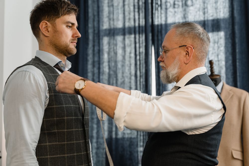 Tailor adjusting a garment on a client during an in-person fitting