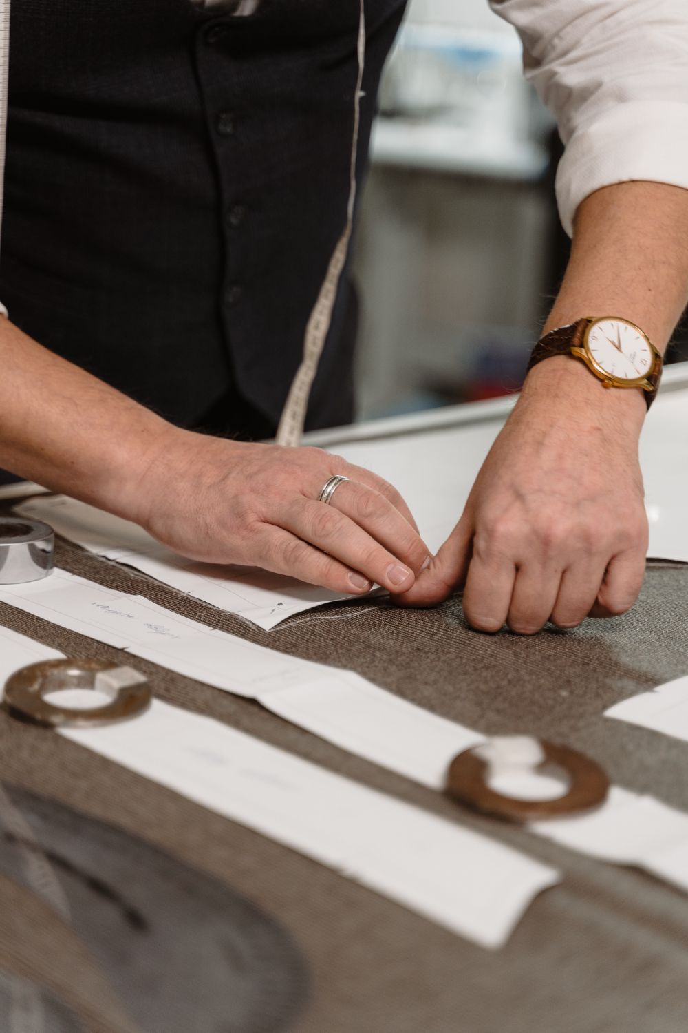 Professional tailor measuring and marking brown fabric on a cutting table