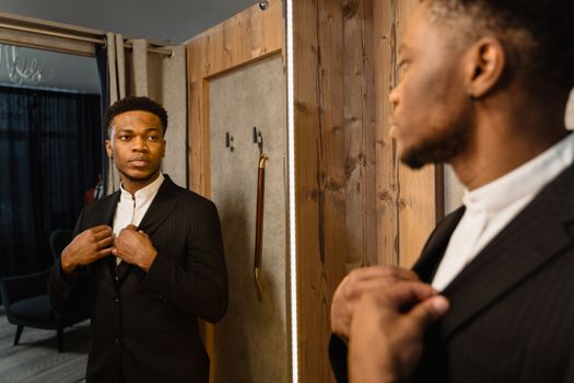 A well-dressed man adjusts his suit, reflecting elegance and style in the mirror.