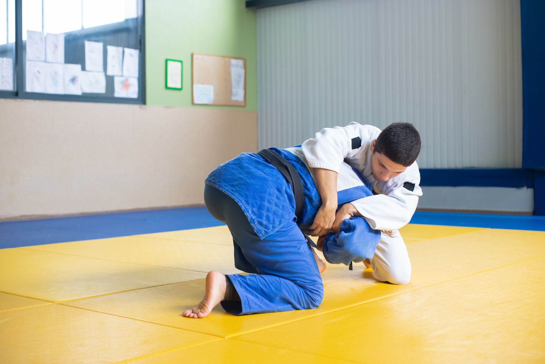 Two men practicing judo techniques on a dojo mat indoors.