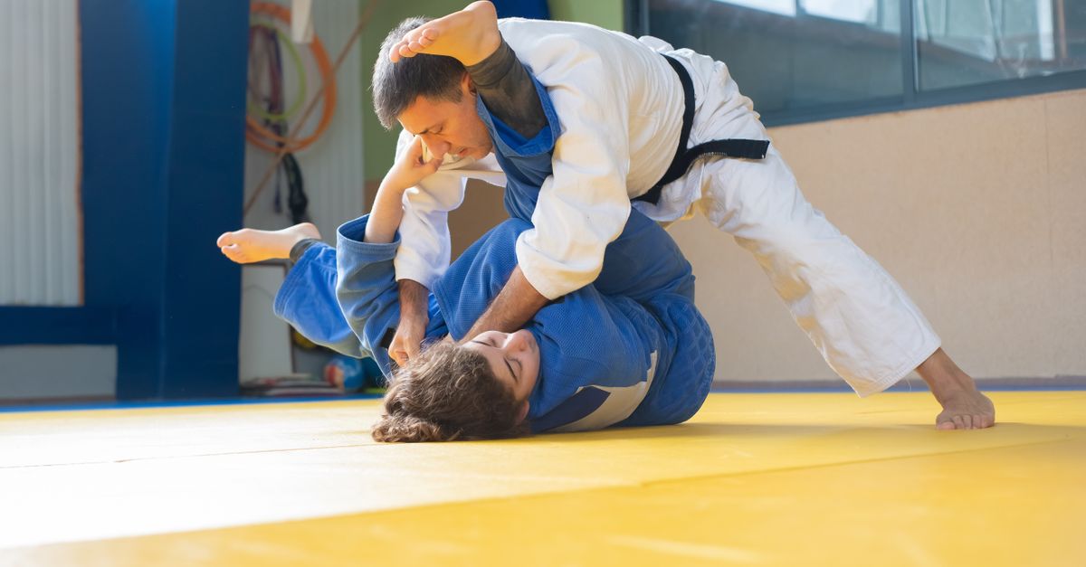 Martial artists practice ground defense and control on yellow mats for an adult self defense training guide.