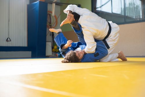 Free A man and woman engage in judo training on a yellow tatami mat indoors. Stock Photo