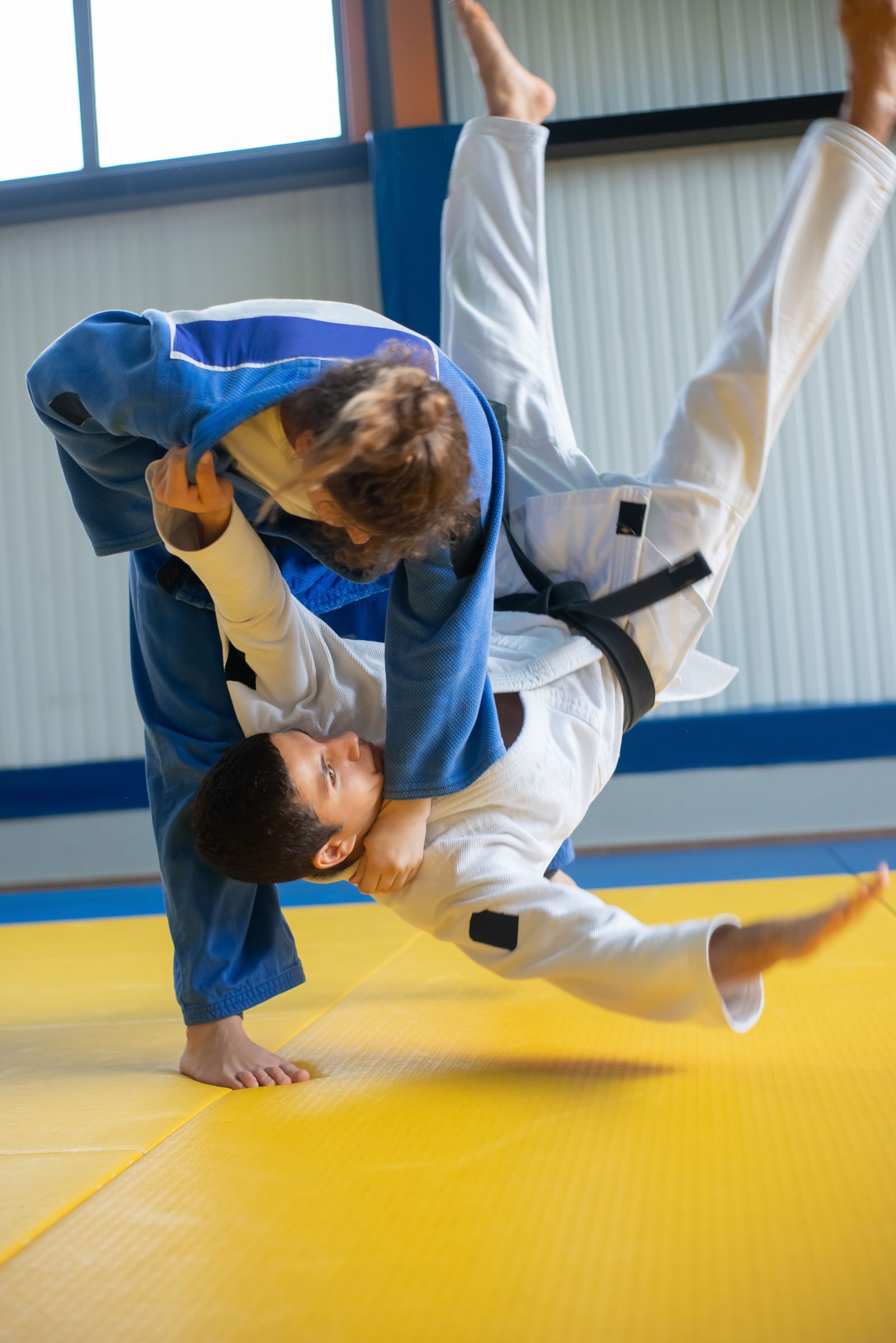 Jiu jitsu athletes in gis during a mat throw, matching knee brace decisions for kneeling, shots, and grappling movement. Photo: Pexels.