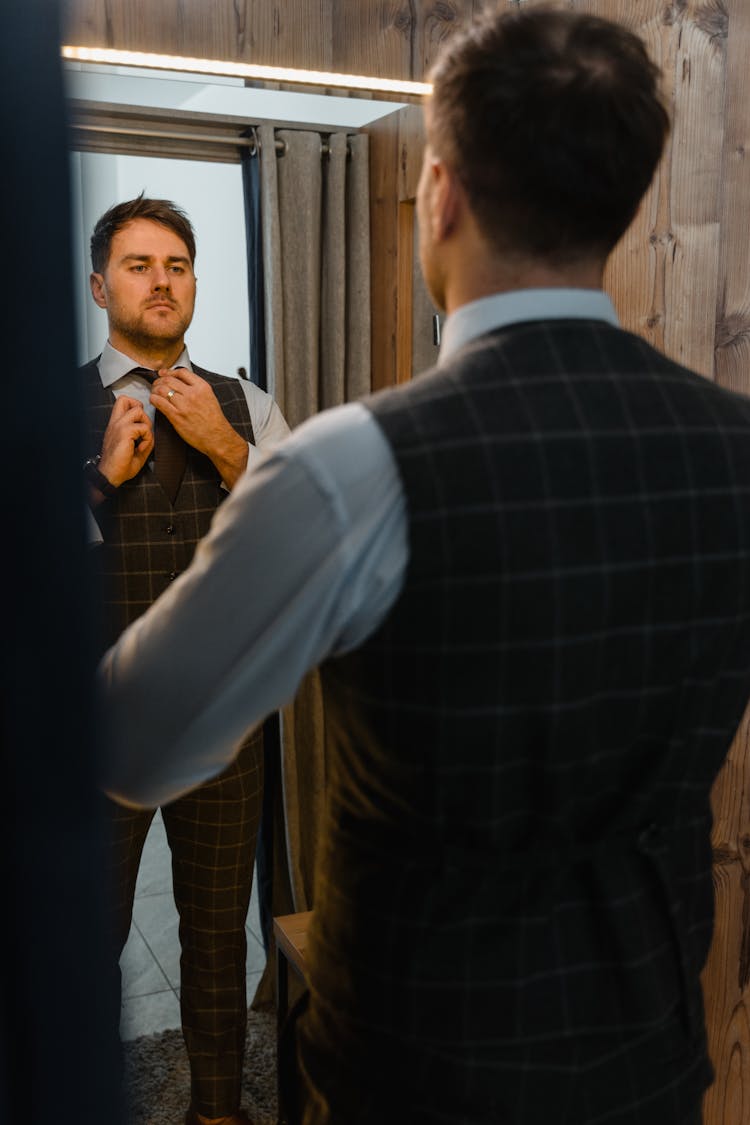 A Man Wearing Vest Looking In The Mirror