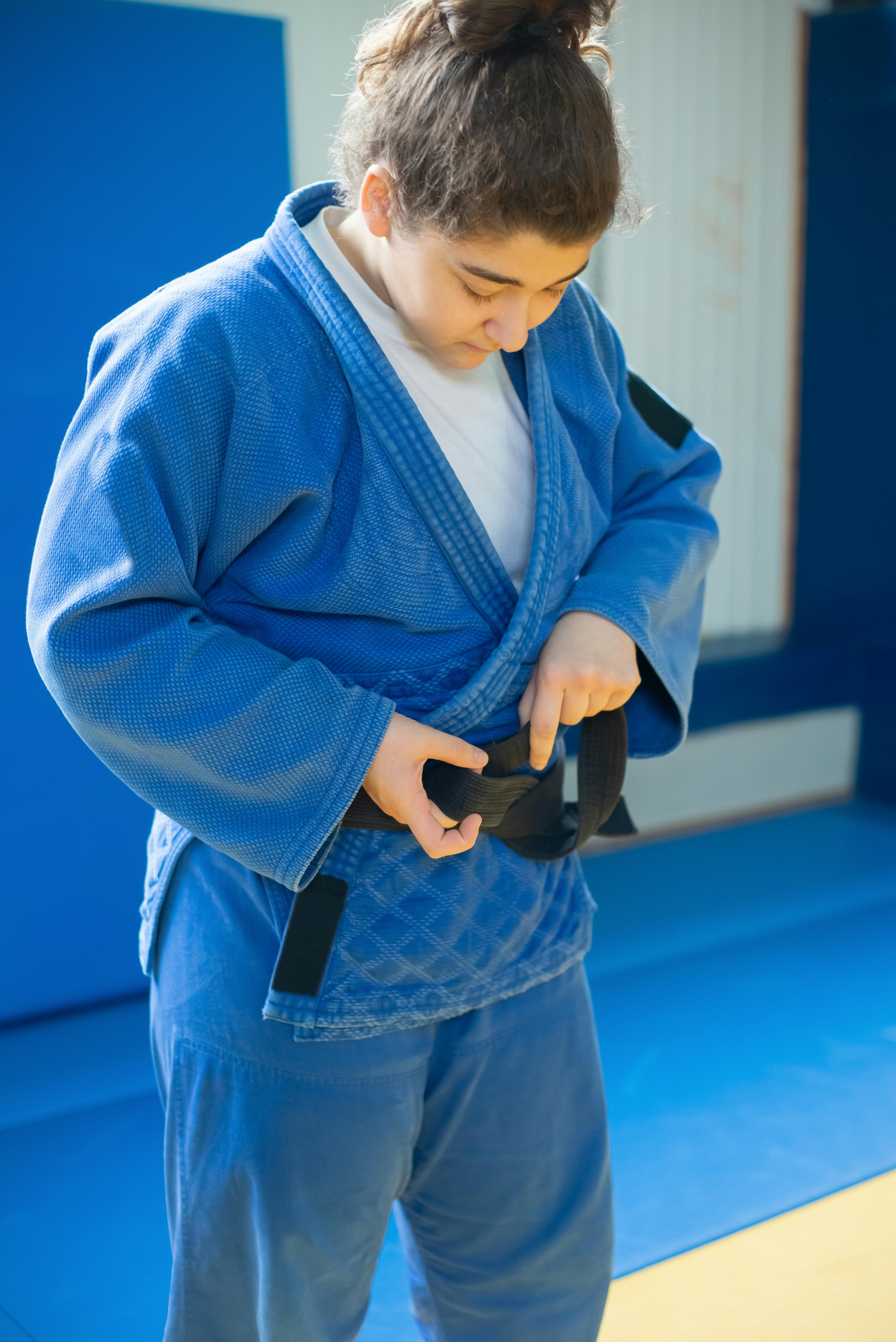 A Woman wearing Judo Uniform fixing her Black Belt  Free Stock Photo
