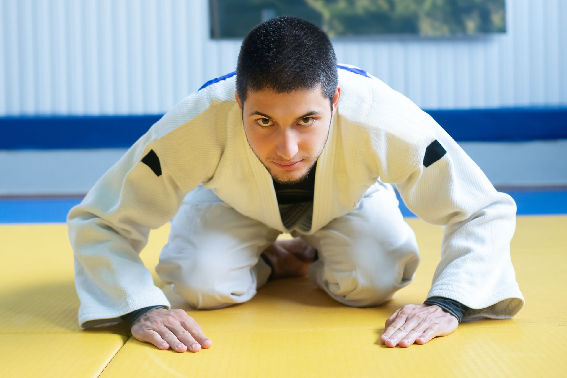 A male judoka bowing on a tatami mat during a judo training session, showing respect and focus.