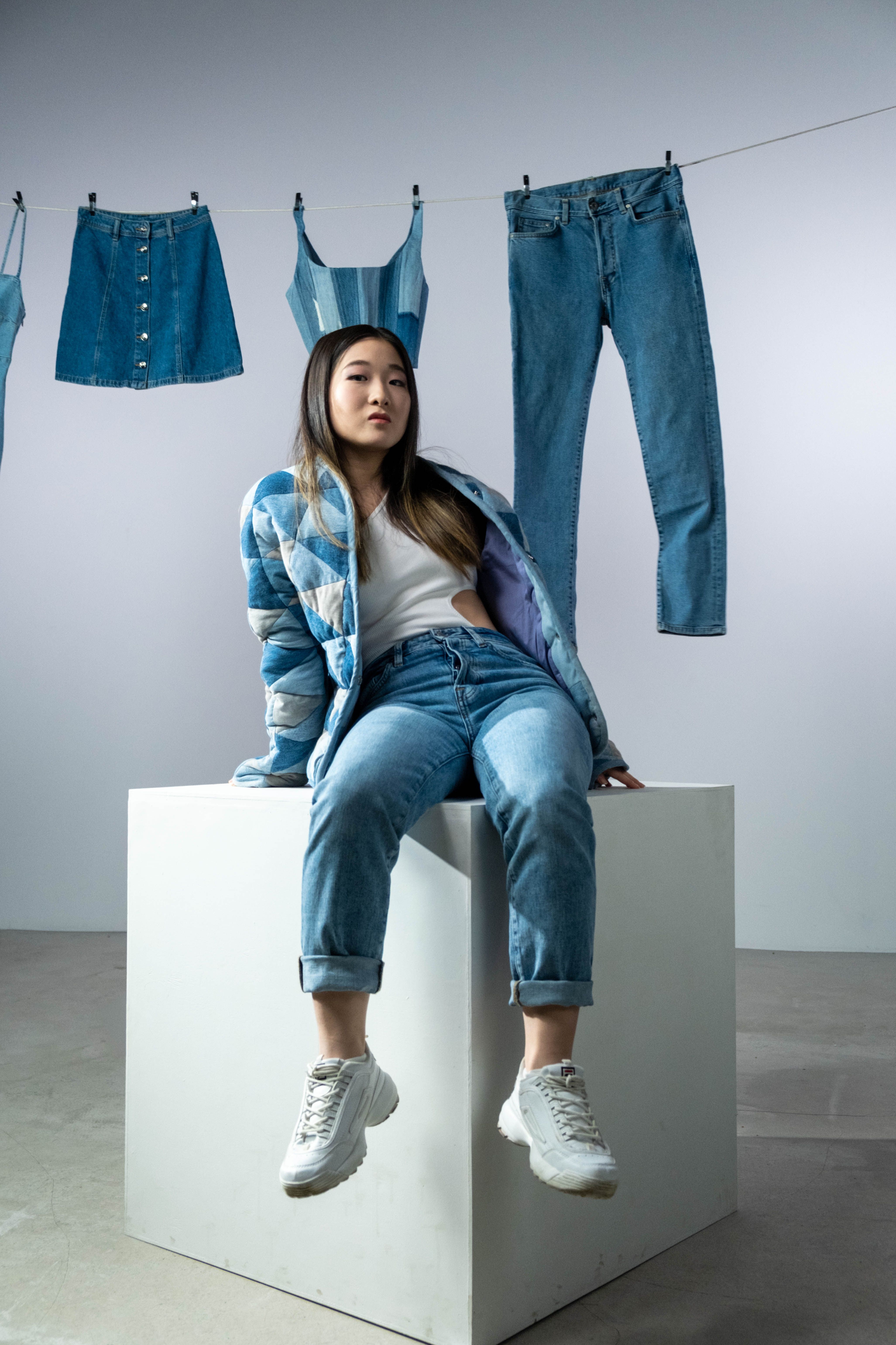 Asian woman posing with denim outfits in an indoor studio fashion photoshoot.
