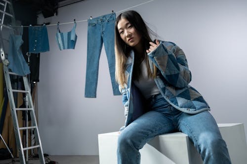 Woman in Blue Denim Jeans Sitting on White Table