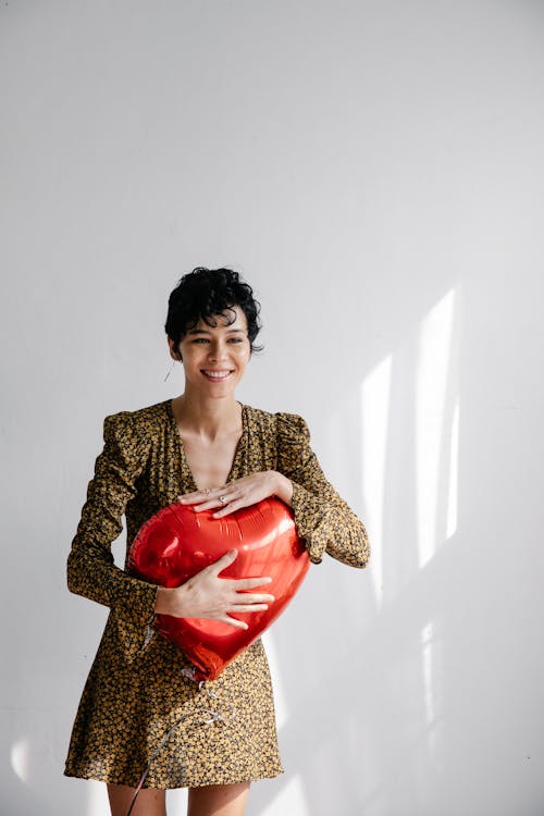 Young stylish woman in trendy dress with heart shaped balloon