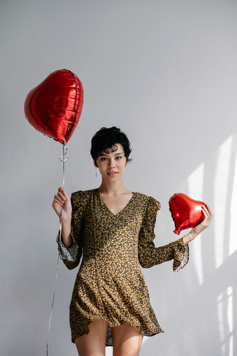 Woman holding two red heart-shaped balloons for Valentine's Day