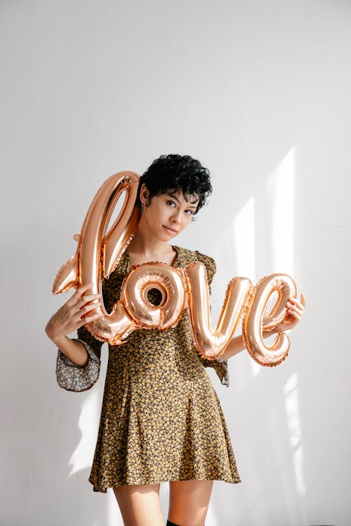 Free Trendy young woman showing sparkling pink balloon with word love Stock Photo