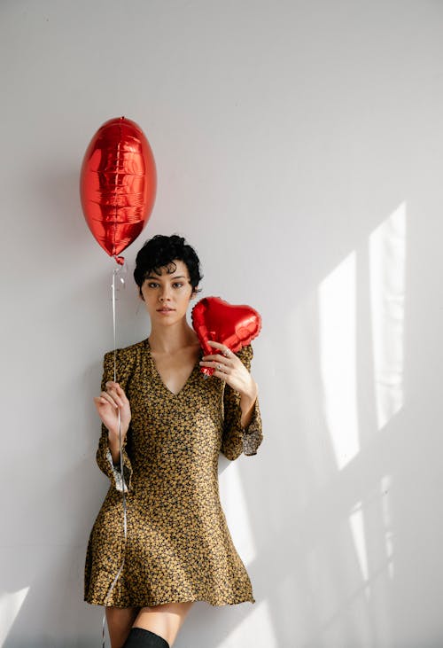 Beautiful Woman holding Two Red Heart-shaped Balloons 