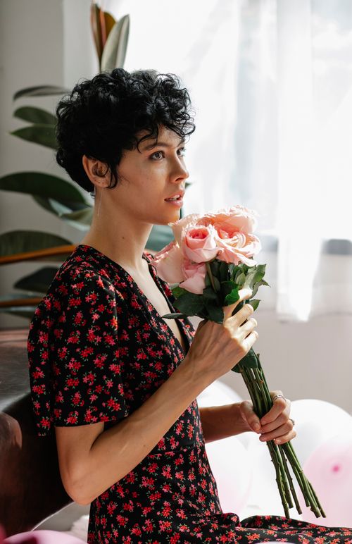 A Woman in Red and Black Floral Dress Holding Red Roses · Free Stock Photo