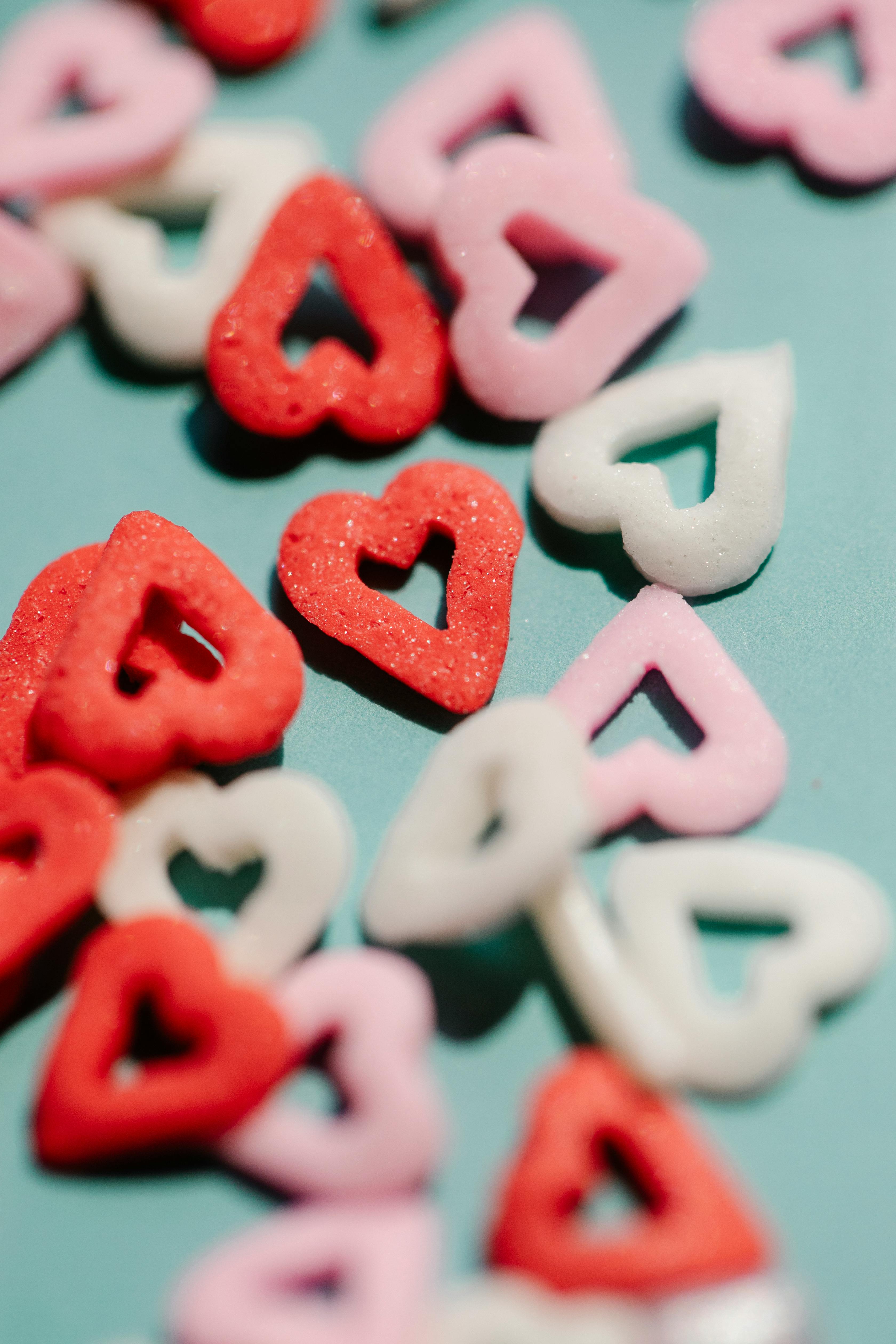 Close-up of colorful heart-shaped candies on a turquoise surface, perfect for Valentine's themes.