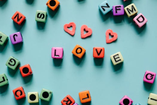 Colorful letter dice spelling 'LOVE' on a blue background with heart shapes.