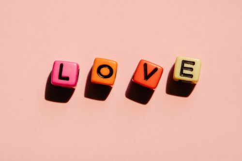 Free Brightly colored blocks spell the word love against a soft pink backdrop, conveying a message of affection. Stock Photo