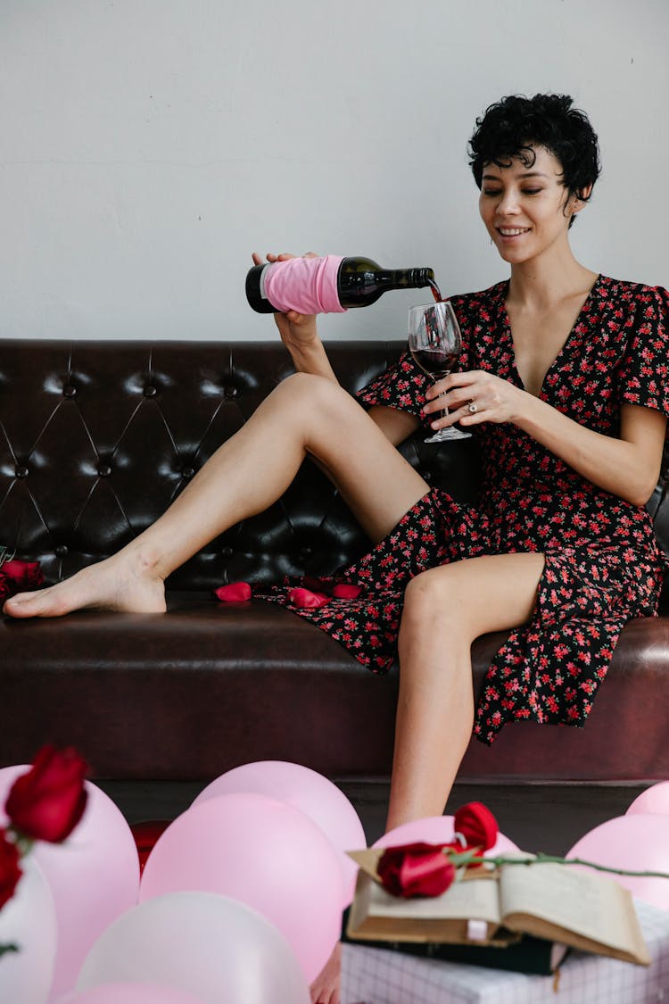 A Woman In Black And Red Dress Pouring Wine In A Wine Glass