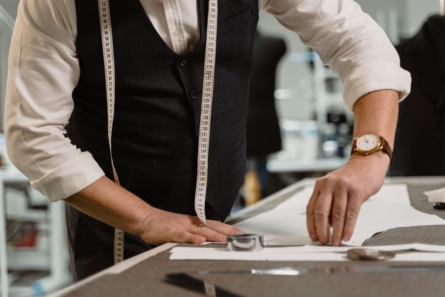 A tailor working fabric by hand at the workbench