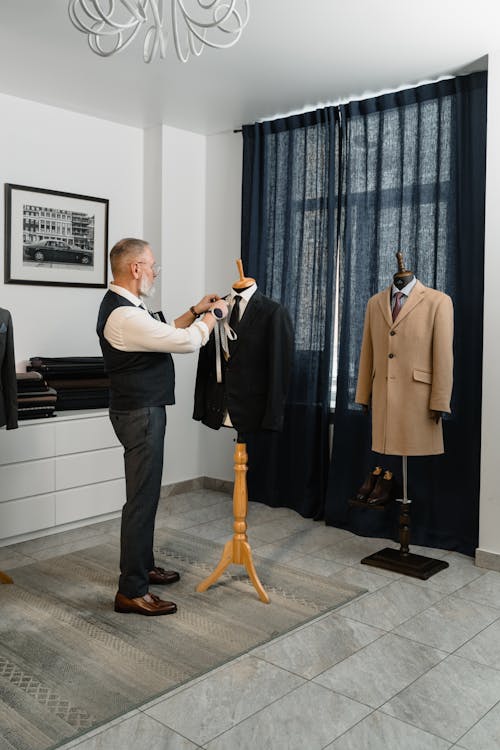 A Man Holding a Tape Measure Fixing a Suit Jacket on a Mannequin