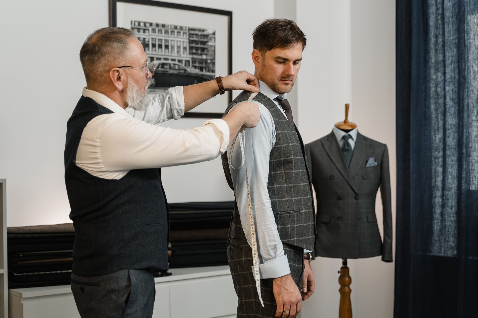 Tailor expertly measuring client for a custom-made suit in a stylish workshop.