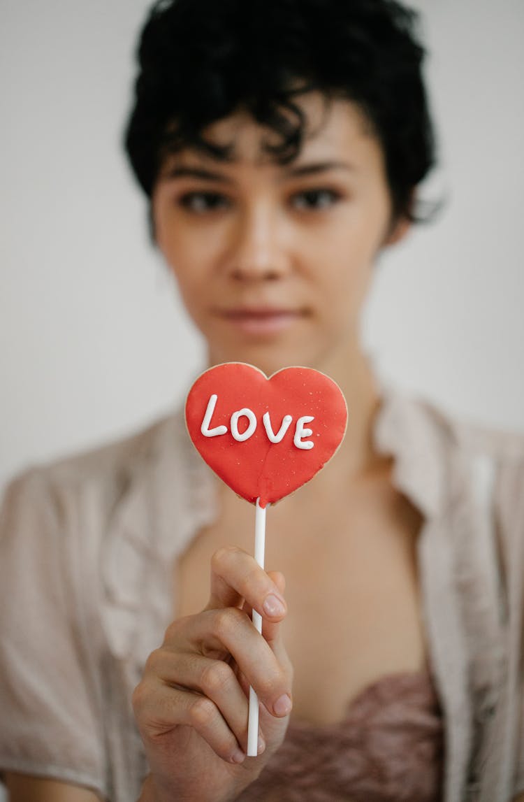 Trendy Young Ethnic Woman Showing Heart Shaped Lollipop