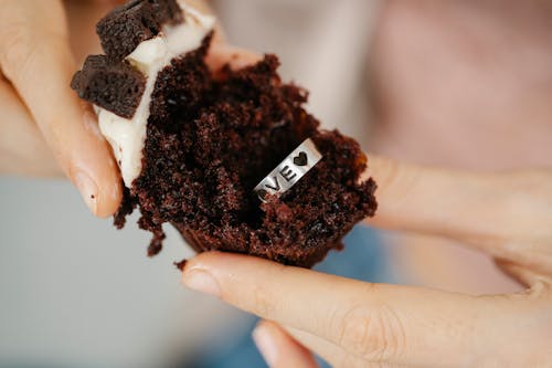 Free Faceless female showing Love engraved silver ring in chocolate muffin Stock Photo