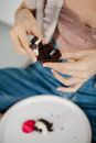 From above of crop anonymous young stylish lady eating delicious sweet chocolate muffin with Love engraved silver ring inside on Saint Valentine Day
