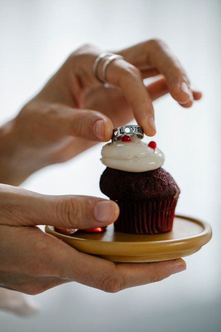 Close-up of hands placing a love ring on a cupcake. Perfect for Valentine's celebrations.