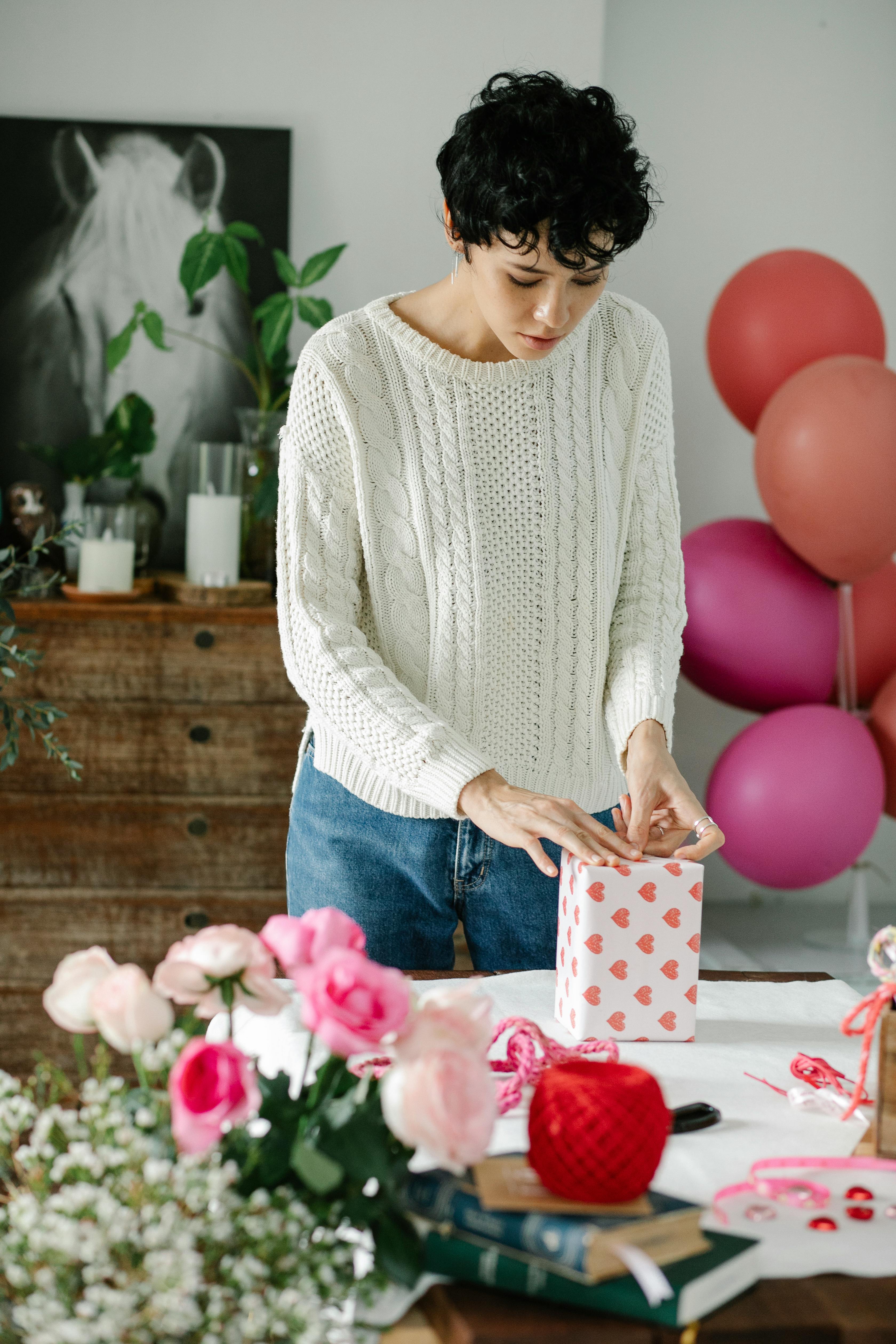 woman preparing gift boxes at table in light apartment