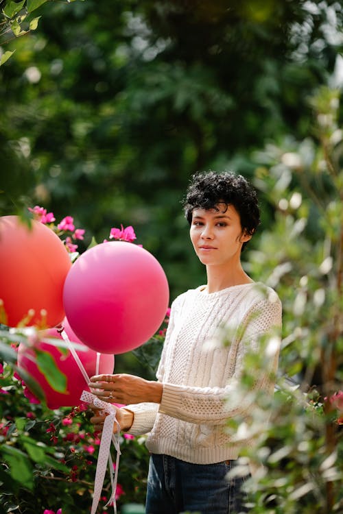 Woman with bright balloons among plants
