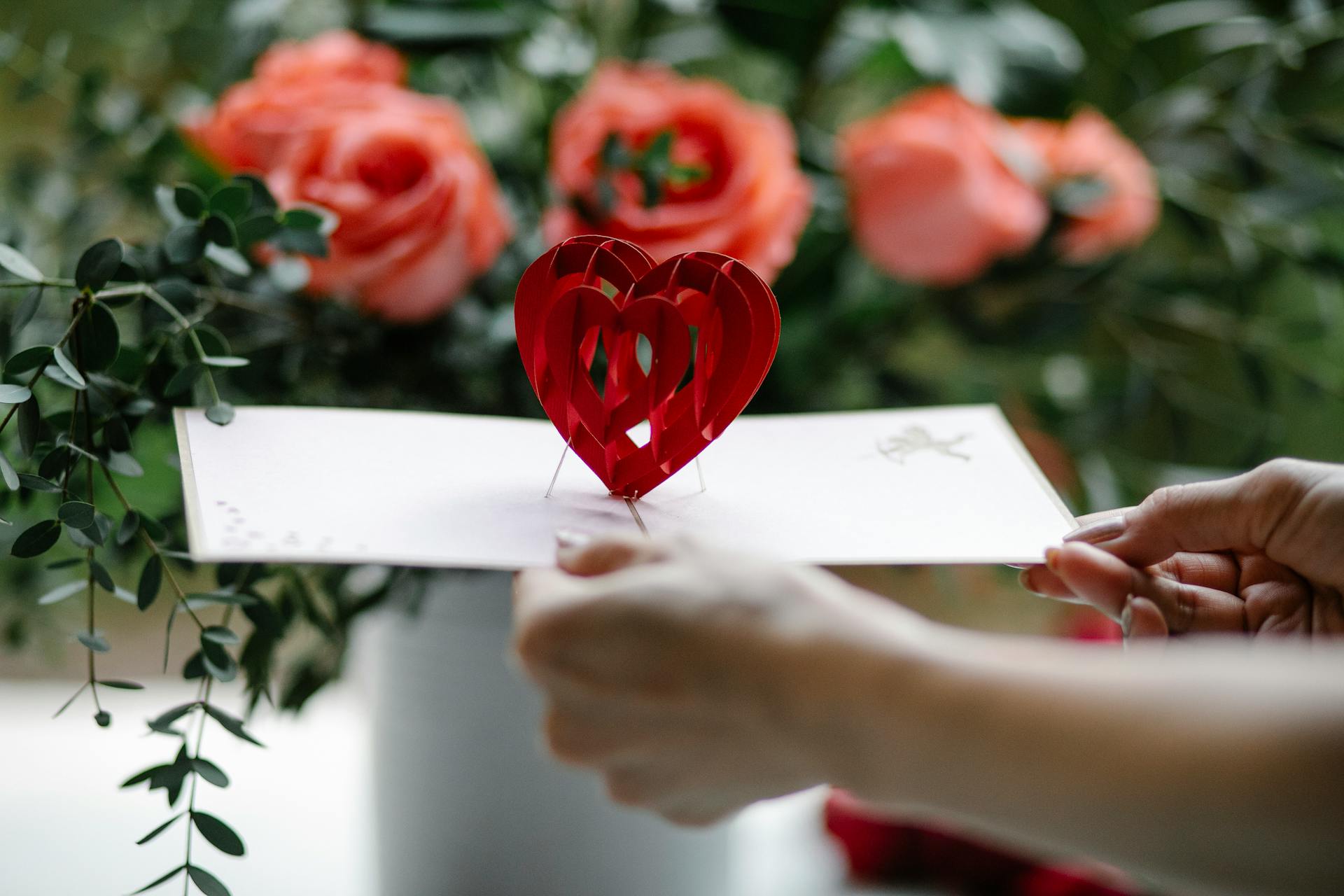 Crop woman showing pop up gift card with decorative heart