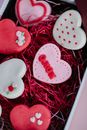 From above of colorful sweet cookies with glaze placed in box with red paper filling during Saint Valentines day celebration