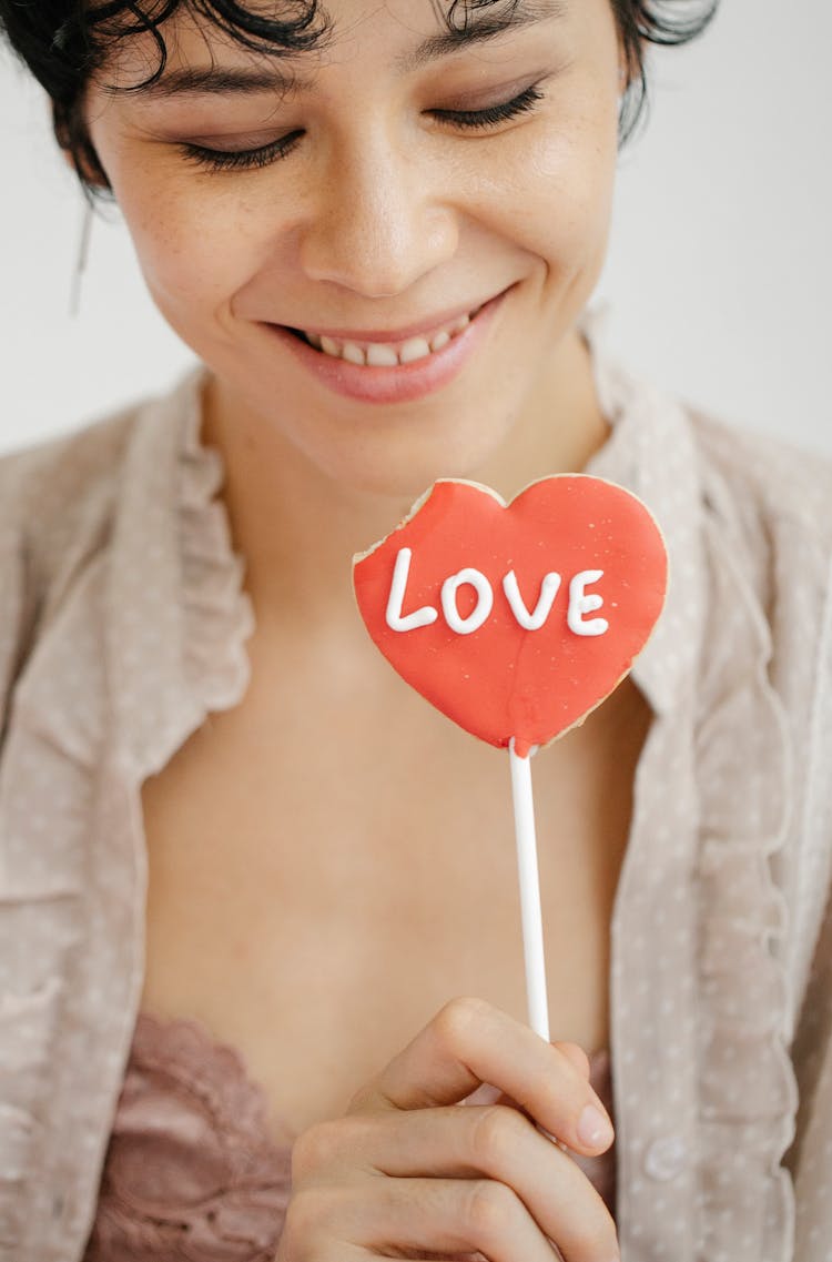 Smiling Woman Eating Heart Shaped Cookie