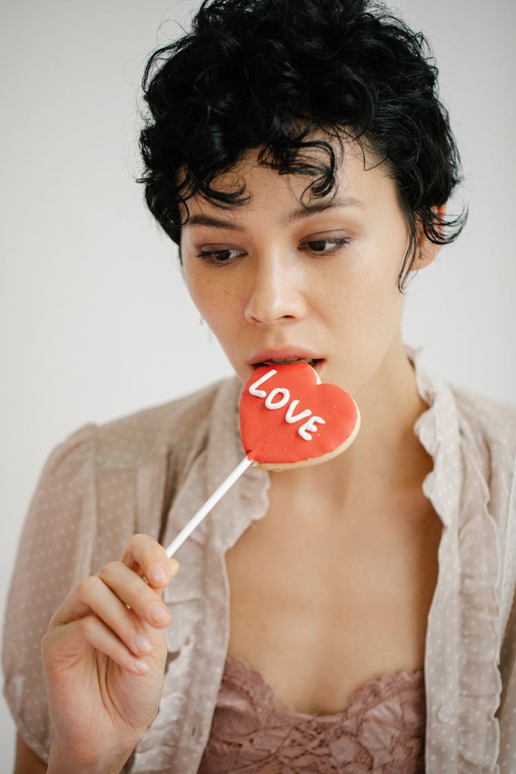 Pensive Woman Eating Heart Shaped Cookie