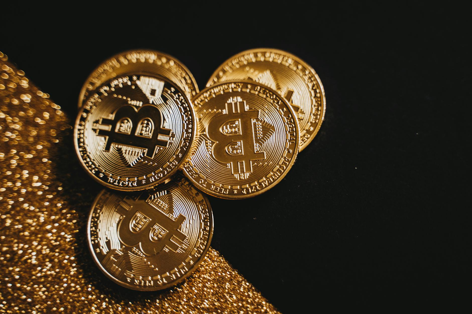 A detailed close-up shot of shiny bitcoin coins resting on a glittery surface, symbolizing wealth in digital currency.