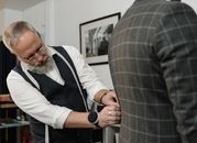 Experienced tailor meticulously adjusting a client's suit jacket in a professional setting.