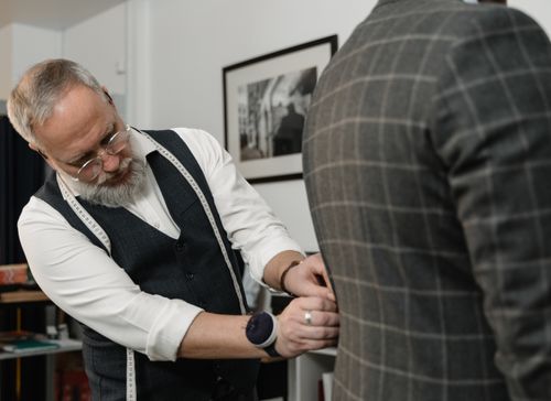 Free Experienced tailor meticulously adjusting a client's suit jacket in a professional setting. Stock Photo