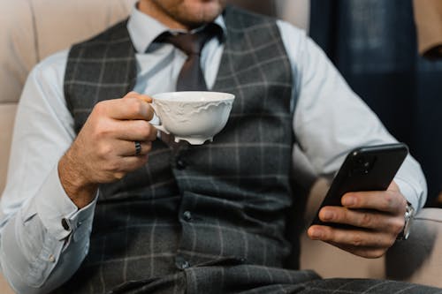 Man in Plaid Waistcoat Holding White Ceramic Teacup