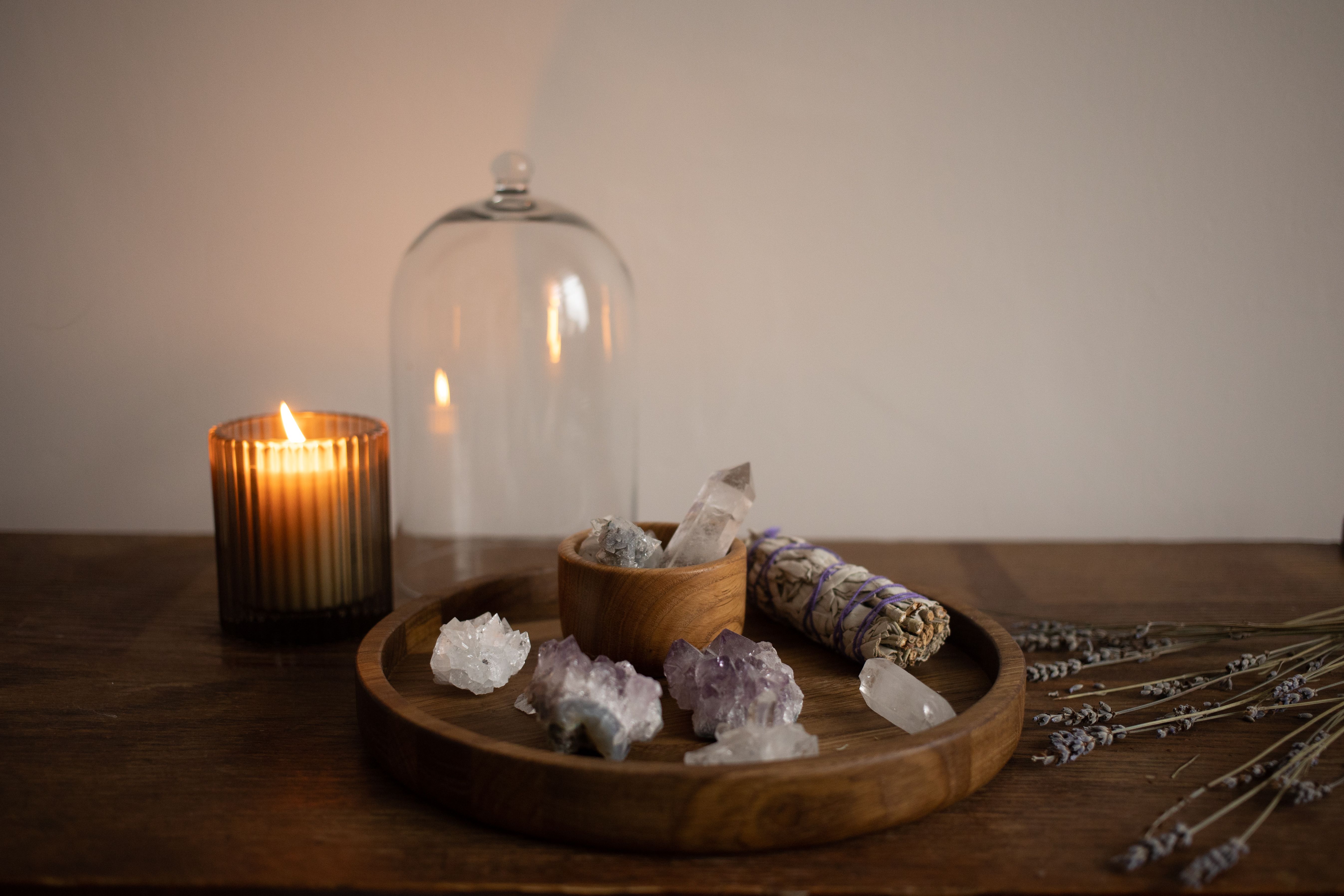 A serene indoor setting featuring crystals, sage, and a candle on a wooden tray.