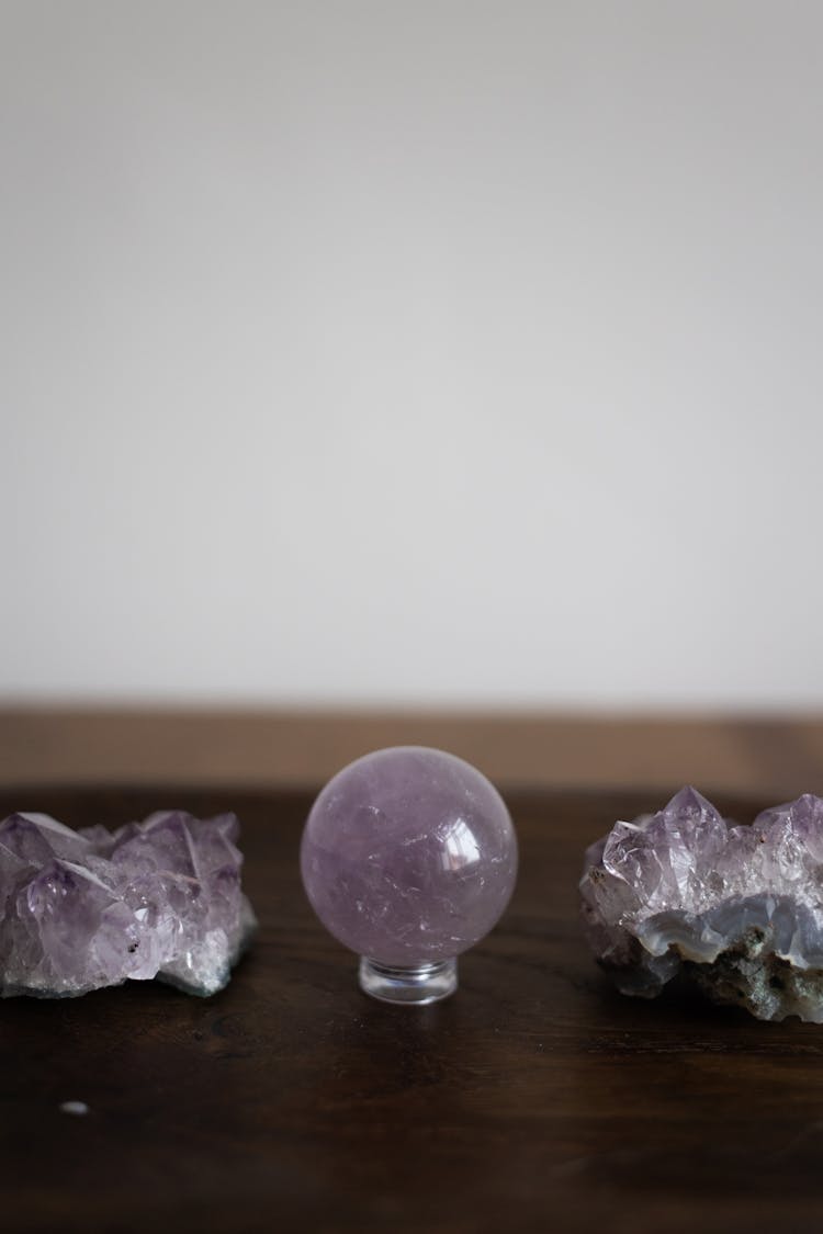 A Crystal  Ball Between Gemstones On A Wooden Table