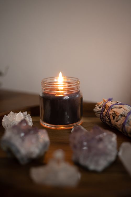 Free Cozy scene featuring a candle, crystals, and sage bundle for spiritual practices. Stock Photo